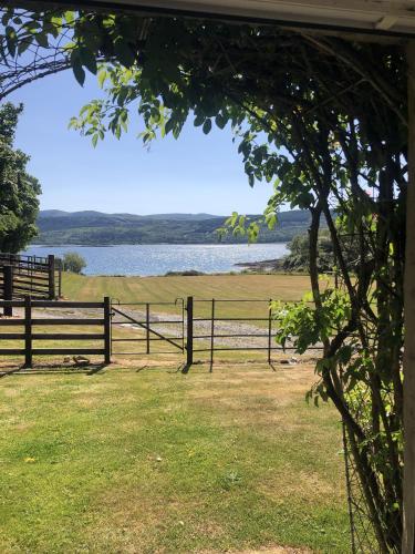 einen Zaun mit Blick auf ein Feld und einen See in der Unterkunft Ellary Cottage in Stonefield
