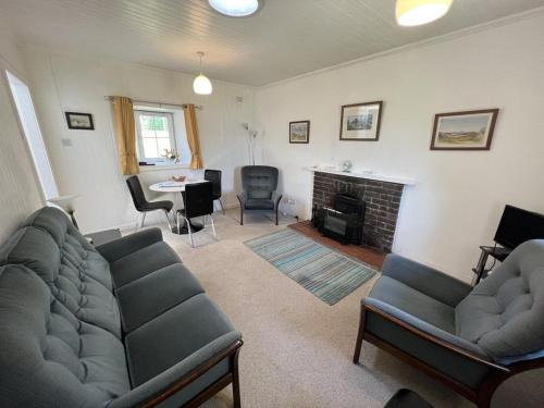 ein Wohnzimmer mit 2 Sofas und einem Kamin in der Unterkunft Ellary Cottage in Stonefield