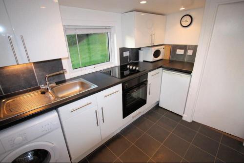 eine kleine Küche mit einer Spüle und einer Mikrowelle in der Unterkunft Ellary Cottage in Stonefield