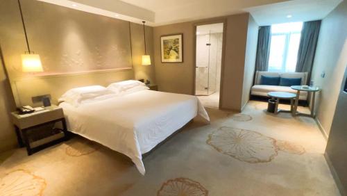 a bedroom with a large white bed and a bathroom at Byland Star Hotel in Yiwu
