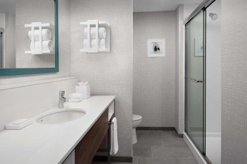 y baño blanco con lavabo y ducha. en Hampton Inn Orlando Southeast Nona en Orlando