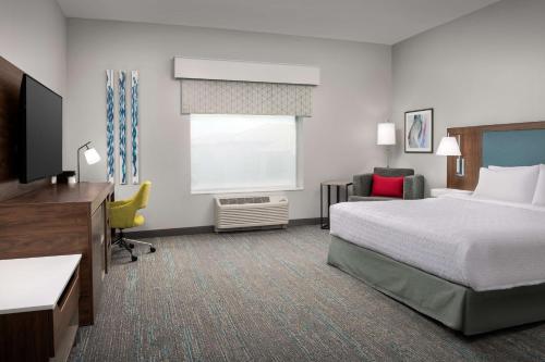 a hotel room with a bed and a desk at Hampton Inn Orlando Southeast Nona in Orlando