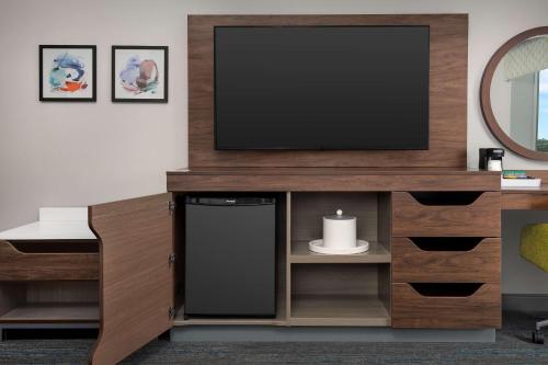 a living room with a television on a wooden entertainment center at Hampton Inn Orlando Southeast Nona in Orlando