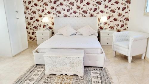 a bedroom with a white bed and a chair at Residence Maresol in Vieste