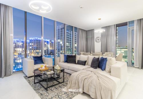 een woonkamer met een witte bank en grote ramen bij Manzil - 3BR + Maid in District One with Burj View in Dubai