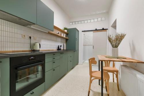 a kitchen with green cabinets and a table and chairs at Charming Apt in Centre /w AC in Bratislava