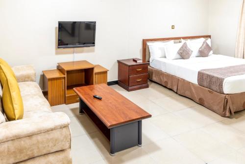 ein Hotelzimmer mit einem Bett, einem TV und einem Sofa in der Unterkunft Emboita Hotel Limited in Nakuru