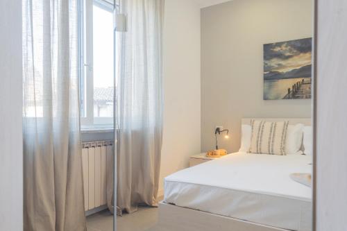 a white bedroom with a bed and a window at Isola Felice Grandate by Rent All Como in Como
