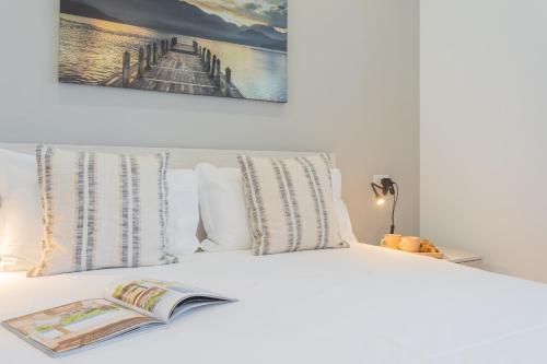 a book laying on top of a white bed at Isola Felice Grandate by Rent All Como in Como