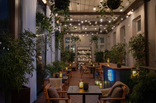 a restaurant with tables and potted plants and lights at Falkensteiner Boutique Hotel Prague in Prague