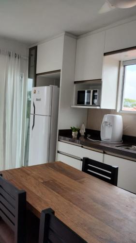 a kitchen with a wooden table and a white refrigerator at Recanto da Sol in Florianópolis