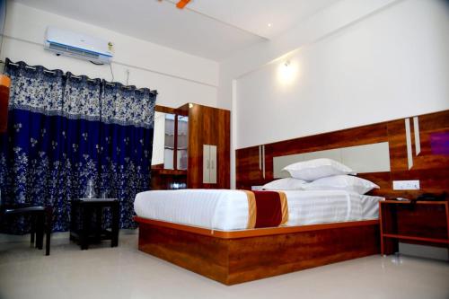 a bedroom with a large bed with a blue curtain at Prince Recidency in Bangalore