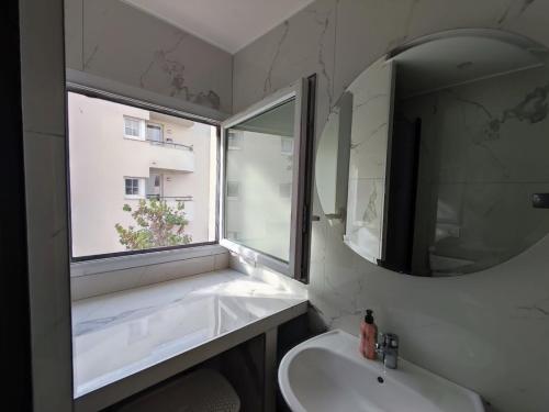 ein Badezimmer mit Waschbecken, Spiegel und Fenster in der Unterkunft Magnifique appartement proche de Paris et de Disney in Lognes