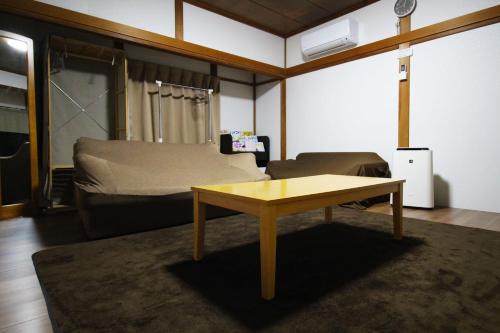 sala de estar con mesa y cama en JR福井駅東口から徒歩7分(550m)。一棟貸切民泊トリプレッツ en Fukui