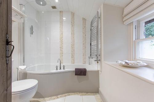 a white bathroom with a tub and a toilet at Goody Bridge Barn in Grasmere