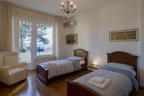 1 dormitorio con 2 camas, silla y lámpara de araña en Sanremo Portosole Roomy Garden Flat, en San Remo