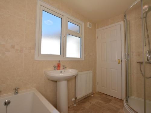 a bathroom with a sink and a window and a bath tub at 2 Bed in Knighton 62209 in Knighton