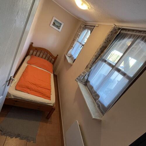 a small bedroom with a bed and a window at Flóra vendégház Tiszafüred in Tiszafüred