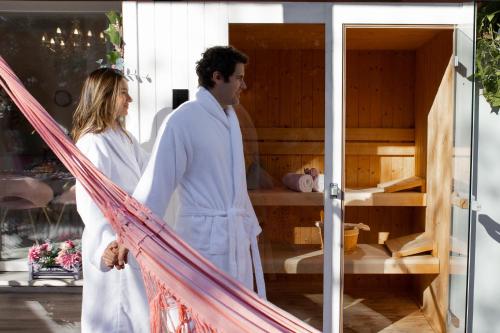 a man and woman in white robes standing on a porch at Esclusiva Villa Romantica con Sauna & Piscina Privata a 10 minuti dall arena di Verona Il Rifugio Perfetto per una Fuga d'Amore in Verona