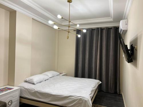 um pequeno quarto com uma cama e um lustre em Mirabad City - 2 em Yakkasaray
