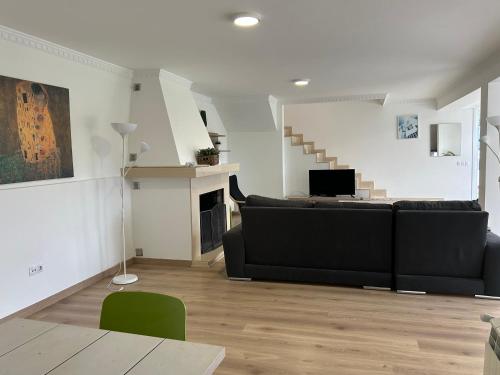 ein Wohnzimmer mit einer schwarzen Couch und einer Treppe in der Unterkunft Apartagal-A Corredoira in Foz