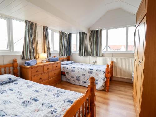 a bedroom with two twin beds and windows at Meadway House in Rhôs-on-Sea