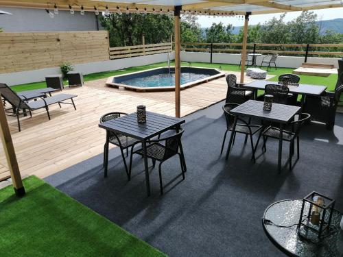 a patio with tables and chairs and a swimming pool at LAPAUSEDEGOUT piscine table d'hôtes chambres climatisées terrasse ou patio in Lachapelle-Auzac