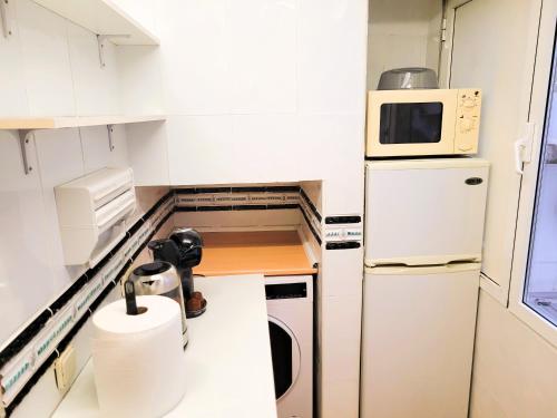 a small kitchen with white cabinets and a microwave at Piso para 4 - Puerta del Sol in Madrid