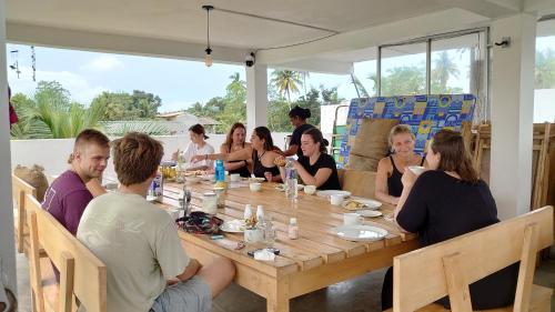 a group of people sitting around a wooden table at Sun & Moon Hostel in Mirissa