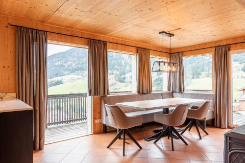 a dining room with a table and chairs and windows at Alpendorf Dachstein West by ALPS RESORTS in Annaberg im Lammertal