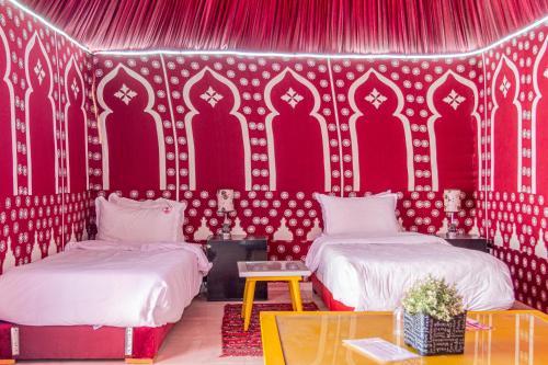 a room with two beds and a red wall at Hotel WOW in Dakhla