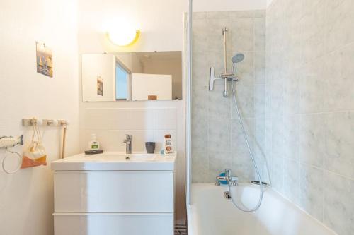 Un baño blanco con lavabo y ducha. en Appart' confort Les Maôves Parking privé, en Étretat