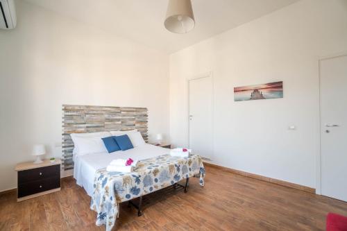 a white bedroom with a bed and a table at CapoSud - Suite Fiocco in Marina di Ragusa
