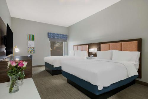 ein Hotelzimmer mit 2 Betten und einem Tisch mit Blumen in der Unterkunft Hampton Inn Linden in Linden
