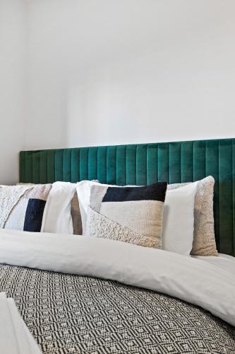 a bed with a green headboard with pillows on it at New Apt Near Smáralind Mall With Private Parking in Reykjavík