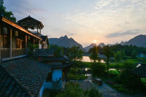 a view of a house and a lake at sunset at Dayong Antique Feature Resort in Zhangjiajie