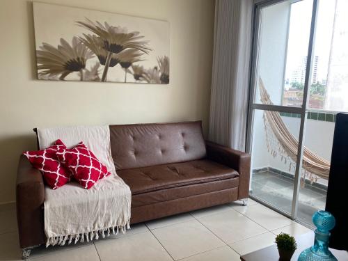 a brown couch in a living room with a window at Ap aconchegante 12 min a pé p Praia in Praia Grande