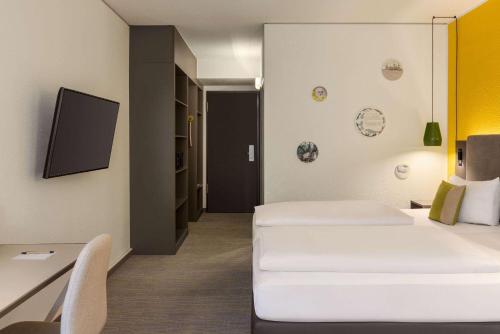 a hotel room with two beds and a tv at Vienna House Easy by Wyndham Leipzig in Leipzig