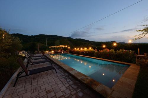 a swimming pool at night with chairs and lights at Agriturismo La Ratta in Vernasca