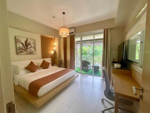 Dormitorio con cama, escritorio y TV en Pico de Loro 2 BD Garden Loft with Lagoon View, en Nasugbu