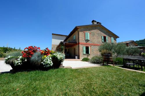 a stone house with a table and flowers in a yard at Agriturismo La Ratta in Vernasca