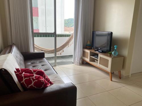 a living room with a couch and a tv at Ap aconchegante 12 min a pé p Praia in Praia Grande