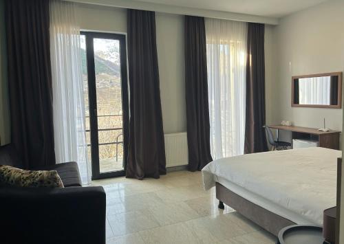 a hotel room with a bed and a desk and window at Shushabandi Kazbegi in Stepantsminda