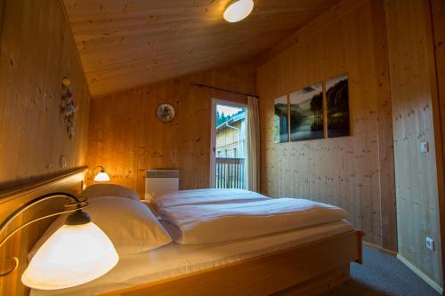 a bed in a wooden room with a window at Alpendorf Dachstein West by ALPS RESORTS in Annaberg im Lammertal