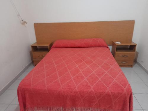 a bed with a red comforter in a room at Departamentos del Sol in Resistencia