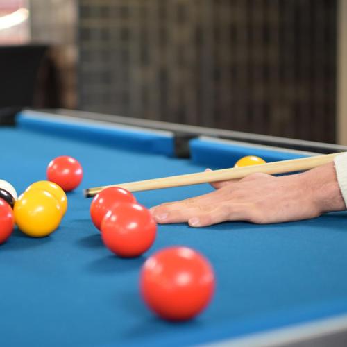 a man playing a game of pool on a pool table at Best Western Plus Le Conquerant Rouen Nord in Bois-Guillaume