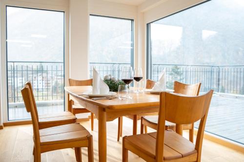 een eetkamer met een tafel, stoelen en ramen bij Penthouse Visp - mit großer Dachterasse und Panoramablick in Visp