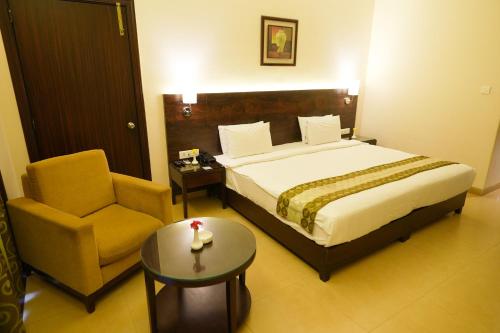 a bedroom with a bed and a chair and a table at Greenleaf The Resort & Spa, Ganpatipule in Ganpatipule