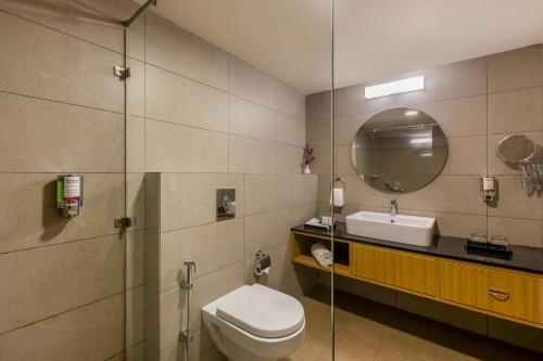 a bathroom with a toilet and a sink and a mirror at Sterling Puri in Puri