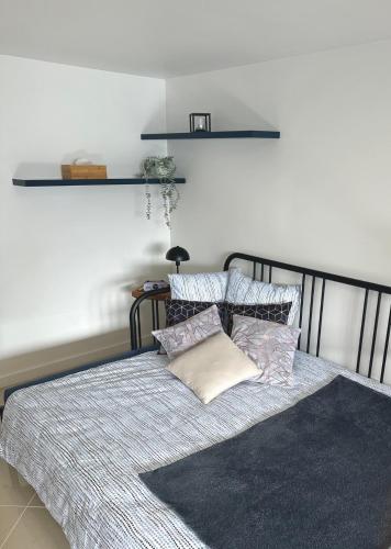 a bedroom with a bed with pillows and a shelf at Petite Maison studio tout confort cosy Givors autoroute et gare in Givors